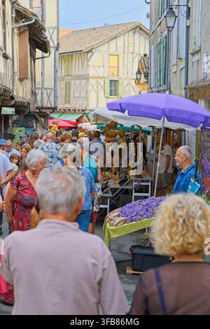 Überfüllter Sonntagmarkt im mittelalterlichen Dorf Issigeac, Dordogne, Frankreich, mit Fachwerkhäusern, Ständen und Sitzplätzen im Freien. Stockfoto