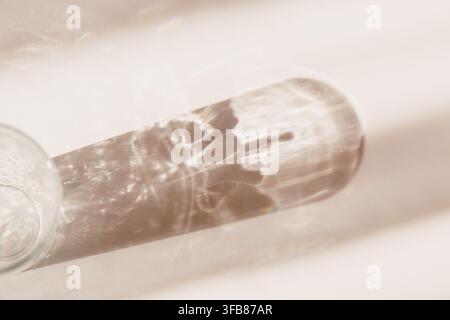 Warmer beiger abstrakter Hintergrund mit zartem Glasschatten und goldenen Lichtreflexionen, minimalistischer Luxus-Hintergrund für Branding-Gluckkarten, Krankenhaus Stockfoto