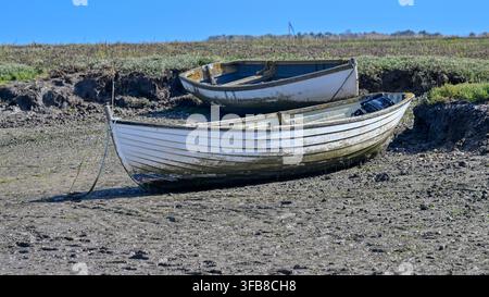 Kleine Boote, die von Muschel Fischern bei Ebbe in Brancaster Staithe, Norfolk, UK, auf Grund liegen Stockfoto