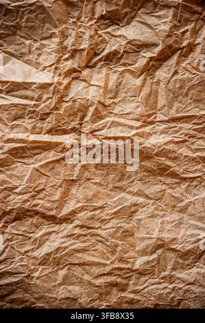 Nahaufnahme der Textur von zerknittertem braunem Kraftpapier mit Falten, Knickstellen und einer unebenen Oberfläche aus recyceltem Papier Stockfoto