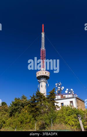 Telekommunikationsturm mit Antennen und Satellitenschüsseln, hoch vor einem klaren blauen Himmel Stockfoto