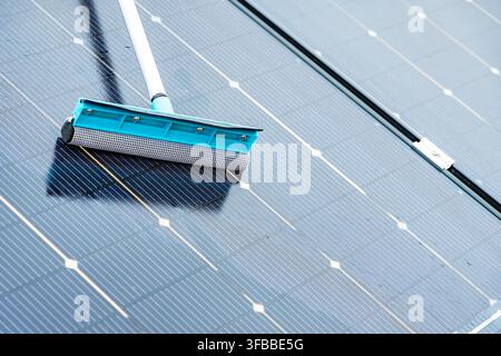Eine Nahaufnahme zeigt ein Abziehwerkzeug, das zur Reinigung der Oberfläche von photovoltaischen Solarpaneln verwendet wird, um maximale Effizienz zu gewährleisten Stockfoto