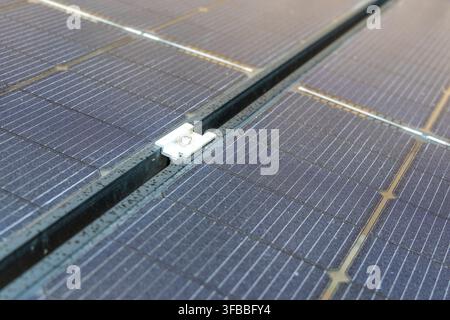 Detailaufnahme, die den Verbindungspunkt zwischen Solarzellen und Montageschienen zeigt, wobei die Photovoltaikzellen und das Gittermuster hervorgehoben werden Stockfoto