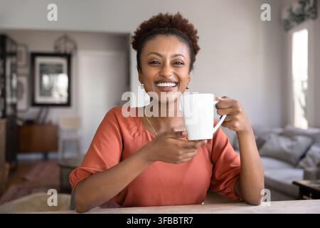 Glückliche Frau genießt ein heißes Getränk zu Hause Stockfoto