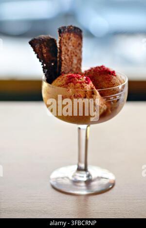 Eiscreme-Dessert mit knusprigen Biscuit-Stäbchen, serviert in einer Glasschale. Stockfoto