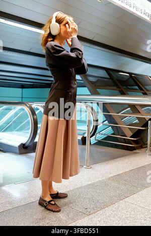 Frau steht in einer U-Bahn-Halle in der Nähe einer Rolltreppe Stockfoto