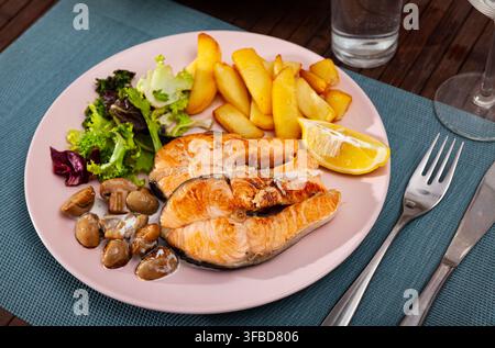 Köstliches gegrilltes Lachsfilet mit einer Garnierung von Kartoffeln und Pilzen Stockfoto