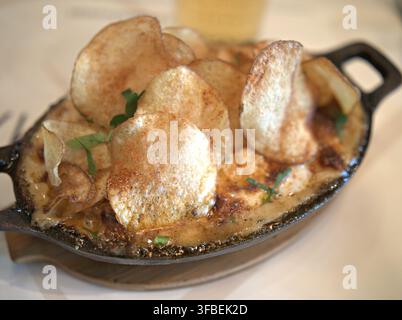 Makkaroni und Käse mit knusprigen Kartoffelchips in der Gusseisenpfanne Stockfoto
