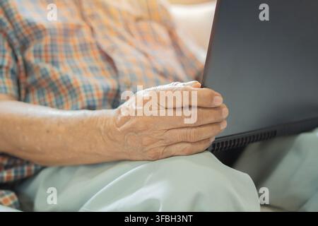 Nahaufnahme der Hände eines älteren Mannes, der einen Laptop hält. Suche nach Informationen im Internet für Rentner. Alte Menschen mit Technologiekonzept. Stockfoto