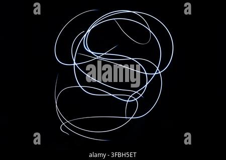Abstrakte Lichtmalerei mit lebendigen leuchtenden weißen gebogenen Streifen, die dynamische Bewegungsmuster auf einem soliden dunklen Hintergrund erzeugen. Stockfoto
