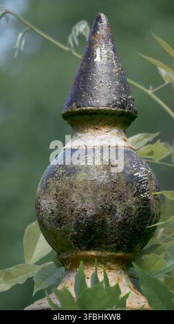 Gusseiser Abschluss, schwarz und gold lackiert, umgeben von Grünpflanzen. Stockfoto
