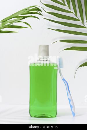 Erfrischendes Mundwasser in einer transparenten Plastikflasche und einer Zahnbürste auf weißem Hintergrund Stockfoto