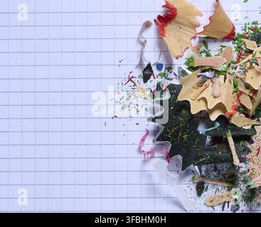 Mehrfarbige Holzspäne von Bleistiften auf Papier, Draufsicht. Kopierbereich Stockfoto