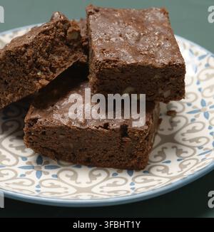 Gebackene quadratische Stücke von Brownie Walnuss Schokoladenkuchen liegen in einem runden Teller, close up Stockfoto
