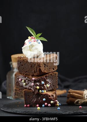 Gebackene Brownie-Schokoladenstückchen auf einem schwarzen Tisch, auf einer Kugel Eis Stockfoto