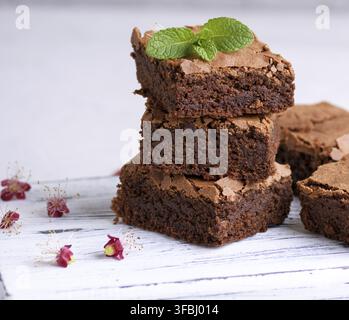 Stapel der quadratische Scheiben gebackene brownie Torte auf ein weißes Holzbrett Stockfoto