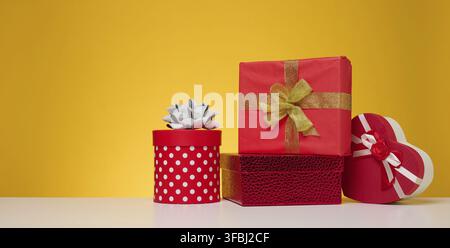 Ein Stapel Geschenkboxen, verpackt in farbenfrohes Papier auf gelbem Hintergrund. Frohe Feiertage Stockfoto