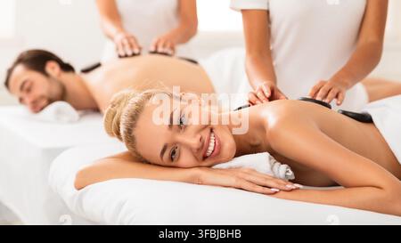 Glücklich Frau Bekommen Stein Massage Auf Paare Spa Verfahren Innen Stockfoto