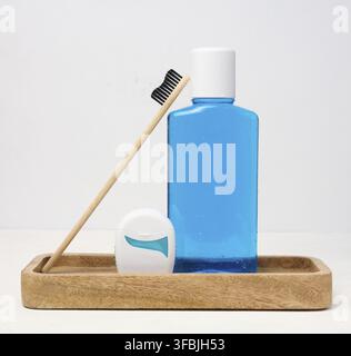 Erfrischende Mundspülung in einer durchsichtigen Plastikflasche und Zahnseide auf weißem Hintergrund Stockfoto