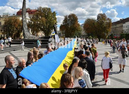 Lviv, Ukraine. 23. Aug., 2026. Ukrainer marschieren mit der Nationalflagge während der Feier. Ukrainer halten eine 35 Meter lange Nationalflagge während einer öffentlichen Veranstaltung zur Feier des Nationalflaggentages in Lviv, Westukraine. Der Nationalflaggentag wird jährlich in der Ukraine am 23. August begangen, um eines der wichtigsten Staatssymbole des Landes zu ehren. Credit: SOPA Images Limited/Alamy Live News Stockfoto