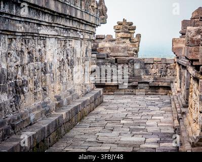 Die kunstvollen Steinreliefs des Borobudur-Tempels zeigen tiefgründige buddhistische Lehren und historische Jataka-Geschichten entlang eines schönen Steinpfades, reflektierend Stockfoto