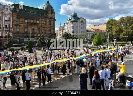 Lwiw, Ukraine. 23. Aug., 2026. Ukrainer marschieren mit der Nationalflagge während der Feier. Ukrainer halten eine 35 Meter lange Nationalflagge während einer öffentlichen Veranstaltung zum Gedenken an den Nationalflaggentag in Lwiw, Westukraine. Der Nationalflaggentag wird jährlich in der Ukraine am 23. August gefeiert, um eines der wichtigsten Staatssymbole des Landes zu ehren. (Foto von Mykola Tys/SOPA Images/Sipa USA) Credit: Sipa USA/Alamy Live News Stockfoto