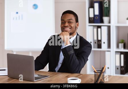 Erfolgreicher afroamerikanischer Geschäftsmann sitzt in seinem Büro Stockfoto