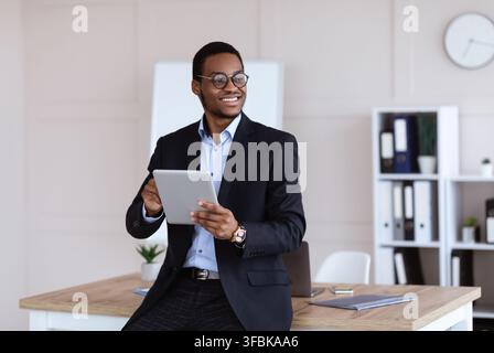 Fröhliche afroamerikanische junge Geschäftsmann mit digitalen Tablet im Büro Stockfoto