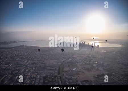 Heißluftballons schweben bei Sonnenaufgang über Doha Stockfoto