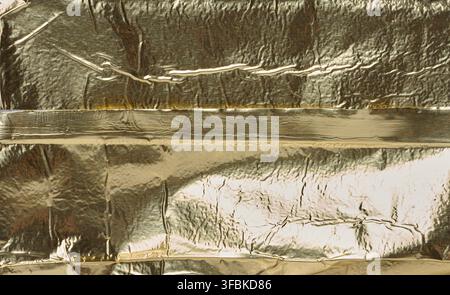 Textur glänzender Goldfolie mit zahlreichen Falten und Falten. Nahaufnahme Stockfoto