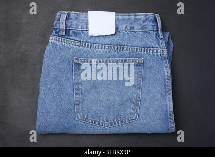 Gefaltete blaue Jeans auf schwarzem Hintergrund, Draufsicht Stockfoto