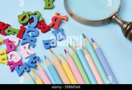 Bunte Holzstifte und Buchstaben auf blauem Hintergrund, Nahaufnahme Stockfoto