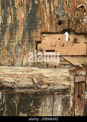 Nahaufnahme eines Teils einer alten, braunen, schäbigen Holztür mit Metallschloss. Stockfoto