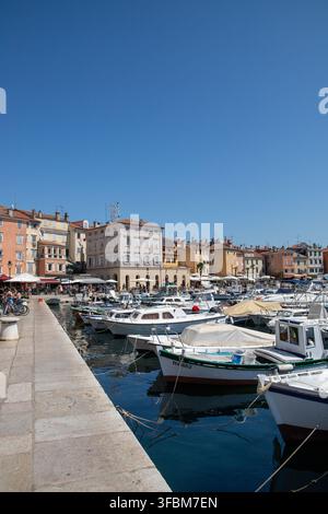 Blick auf den Hafen in Rovinj mit farbenfrohen historischen Gebäuden, festgemachten Booten und einem SteinKai unter einem klaren blauen Himmel in Rovinj, Istrien, Kroatien Stockfoto