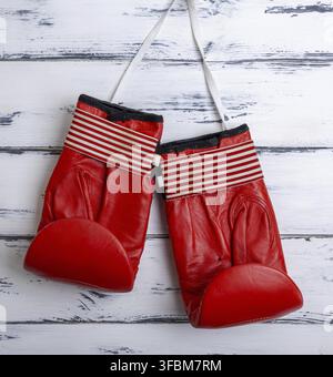 Paar Leder verschlissen roten Boxhandschuhe hängen an einem weißen Spitzen, weißen Holz- Hintergrund Stockfoto