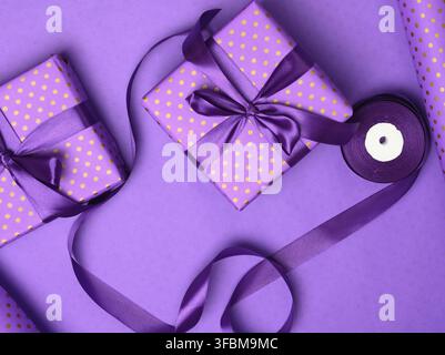 Lila Geschenkbox in Seidenband auf einem lila Hintergrund, Draufsicht eingewickelt Stockfoto