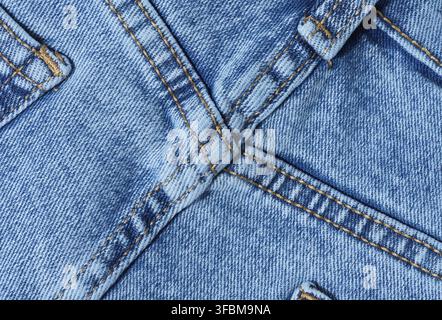 Nahaufnahme aus blauem Denim-Jeans-Material mit verstärkten Kreuznähten. Detaillierte Ansicht der Naht und Textiloberfläche für Design- und Qualitätsthemen Stockfoto