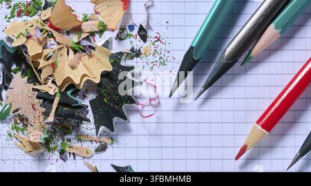 Bleistiftspäne und -Feilen liegen auf einem Stück quadratischem Papier, Draufsicht Stockfoto