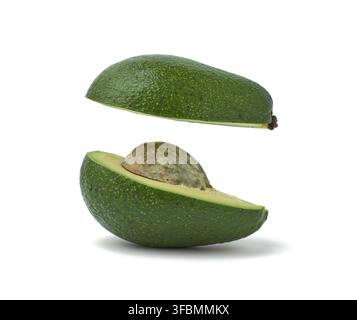 Schneiden Sie die reife grüne Avocado mit dem Knochen auf dem weißen Hintergrund isoliert, die Wirkung der Levitation der Hälften im Raum auf dem weißen Hintergrund Stockfoto