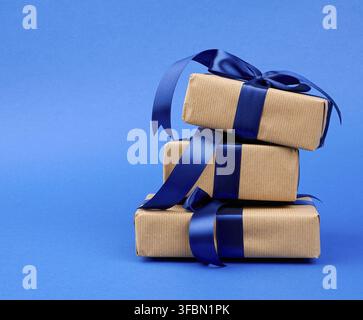 Rechteckbox in braunem Kraftpapier eingewickelt und mit seidenblauem Band, Geschenk auf dunkelblauem Grund, gefesselt Stockfoto