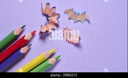 Mehrfarbige Holzstifte und -Späne auf violettem Hintergrund, Draufsicht Stockfoto