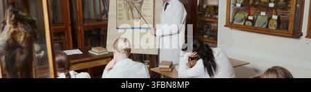Kopf eines mittelalten kaukasischen Professors, der eine vielfältige Gruppe junger Medizinstudenten im Anatomiemuseum unterrichtet. Ideal für Universitätsrekrutierung und Marketing in der medizinischen Bildung Stockfoto