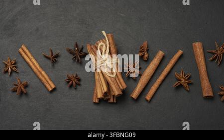 Zimtstangen und Sternanis sind auf einem dunklen, strukturierten Hintergrund verstreut. Draufsicht Stockfoto