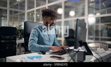 Hinduischer Geschäftsmann computerchatend mit Kundenprojekt, Entwicklung eines arabischen Geschäftsmannes mit moderner Technologie, ethnischer Mann am Schreibtisch im Büro arbeitend Stockfoto