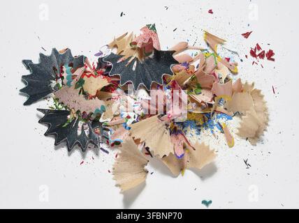 Bunte Bleistiftspäne und kleine Sägemehl liegen auf einem willkürlichen Haufen auf weißem Hintergrund. Draufsicht Stockfoto