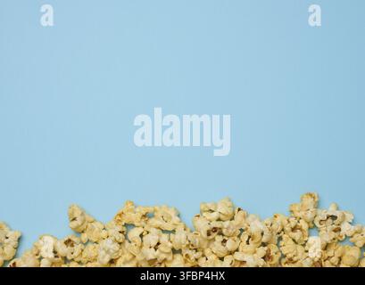 Haufen gebratenes Popcorn mit Käse auf blauem Hintergrund, Draufsicht. Speicherplatz kopieren Stockfoto