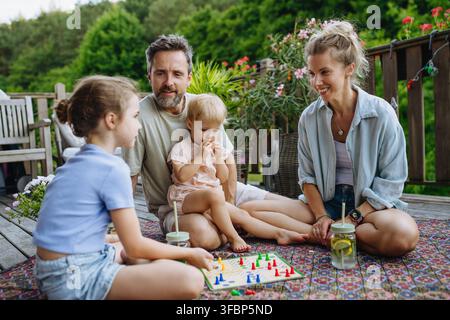 Familie genießt ein Brettspiel zusammen auf der Außenterrasse im Sommer. Stockfoto