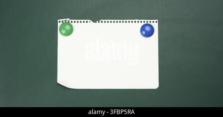 Leere weiße A4-Papier, das an einer grünen magnetischen Tafel hängt. Platz für die Beschriftung Stockfoto