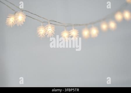 Ansicht einer Lichterkette in Form von Tannenzapfenlichtern im Hintergrund mit Kopierplatz. Weihnachtsgirlanden und Lichtdekoration. Selektiver Fokus Stockfoto