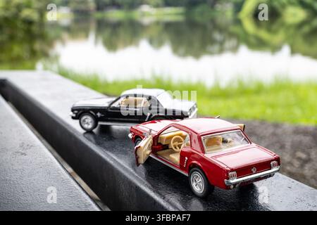 Chiang Mai, Thailand - 17. August 2026 : Gießkanne rote und schwarze Ford Mustang 1964 1/2 Modellautos, die zusammen am Ang Kaew-Stausee, CMU, geparkt sind Stockfoto